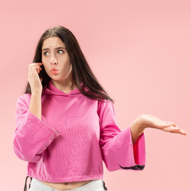 Mujer hermosa joven con estudio de teléfono móvil en estudio de color rosa.