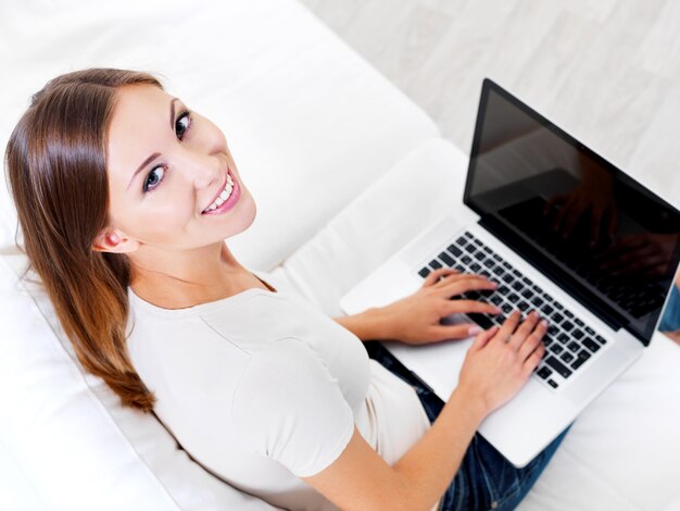 Mujer hermosa joven feliz con laptop - en el interior