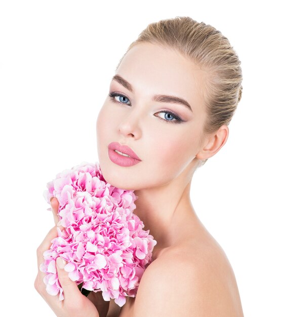 Mujer hermosa joven con flores junto a la cara.