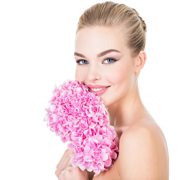 Mujer hermosa joven con flores junto a la cara.