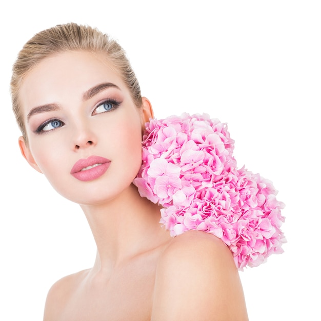 Mujer hermosa joven con flores junto a la cara.