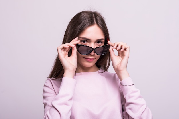 Mujer hermosa joven con gafas de sol sobre un fondo blanco