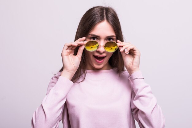 Mujer hermosa joven con gafas de sol sobre un fondo blanco