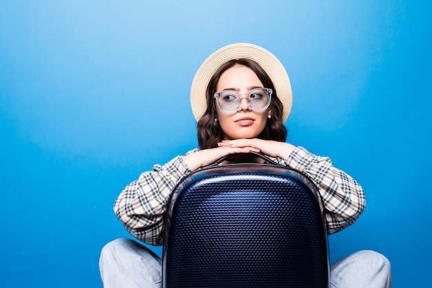 Mujer hermosa joven con gafas de sol y sombrero de paja con maleta con pasaporte antes del vuelo esperando avión