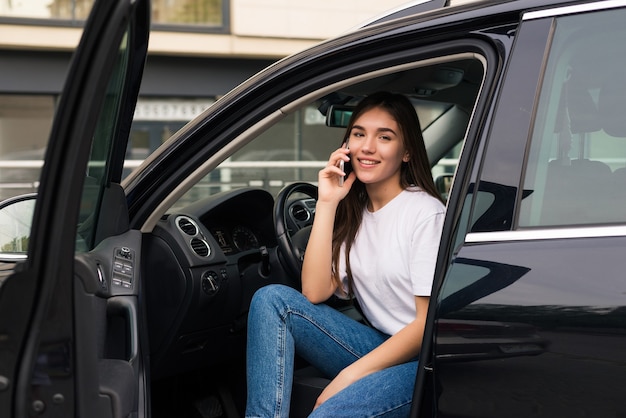 Mujer hermosa joven hablando por teléfono sentado en el coche