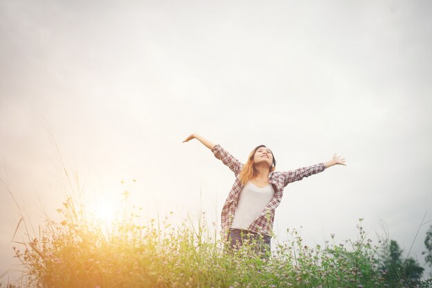 Mujer hermosa joven inconformista en un campo de flores al atardecer. Liberado