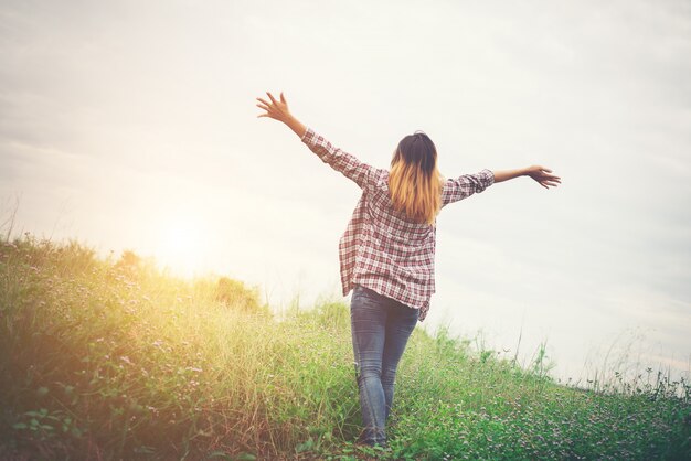 Mujer hermosa joven inconformista en un campo de flores al atardecer. Liberado