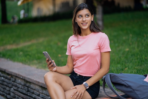 Mujer hermosa joven inconformista con teléfono inteligente en el paquete