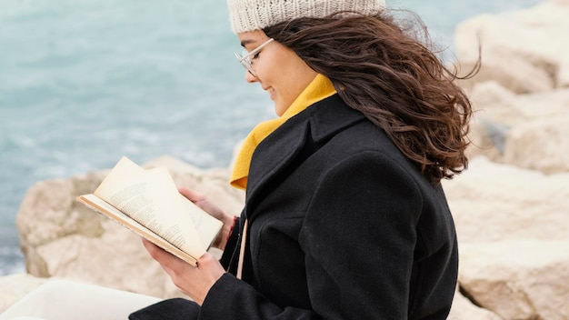 Mujer hermosa joven en el libro de lectura de la naturaleza