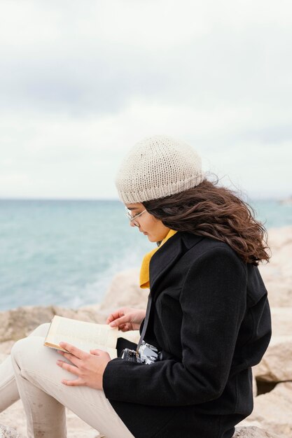 Mujer hermosa joven en el libro de lectura de la naturaleza