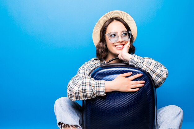 Mujer hermosa joven con maleta con gafas de sol y sombrero de paja listo para viaje de verano