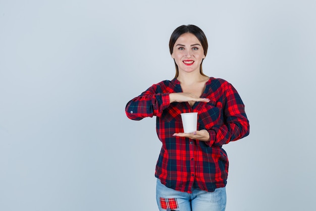 Foto gratuita mujer hermosa joven con la mano sobre el vidrio de plástico en camisa casual, jeans y mirando alegre, vista frontal.