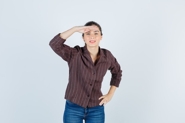 Mujer hermosa joven con las manos sobre la cabeza en la chaqueta y mirando alegre, vista frontal.