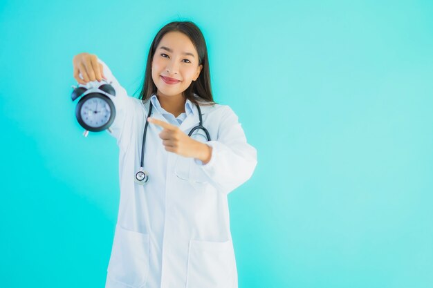 mujer hermosa joven médico asiático con reloj o alarma