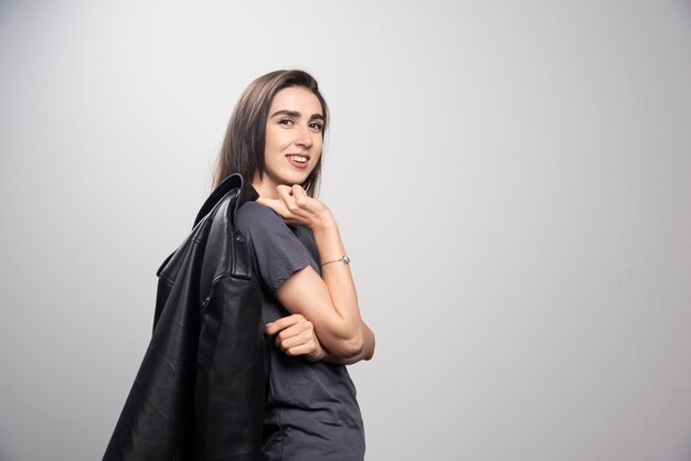 Mujer hermosa joven de moda que presenta en la chaqueta de cuero negra.