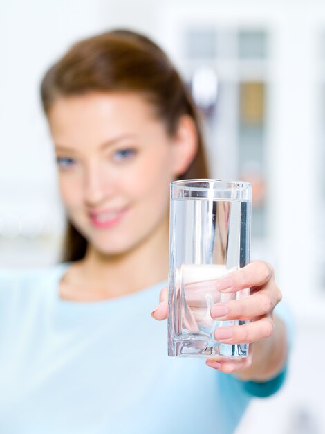 Mujer hermosa joven muestra un vaso de agua