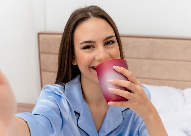 Mujer hermosa joven en pijama azul acostado en la cama