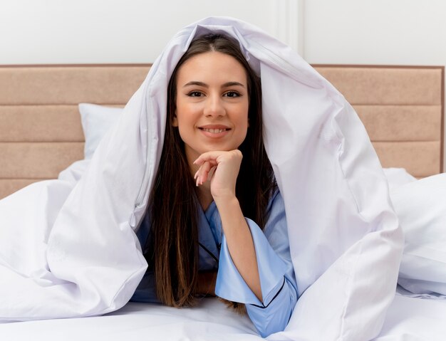 Mujer hermosa joven en pijama azul acostado en la cama