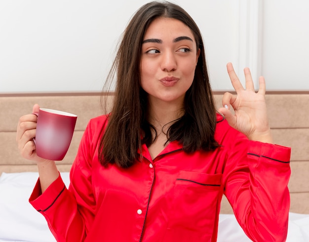 Foto gratuita mujer hermosa joven en pijama rojo relajante en la cama