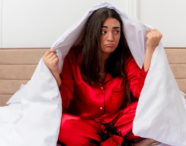 Mujer hermosa joven en pijama rojo relajante en la cama