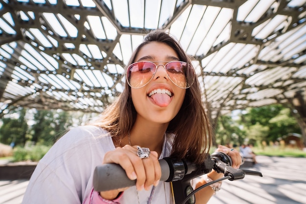 Mujer hermosa joven provocando y mostrando la lengua a la cámara en el parque