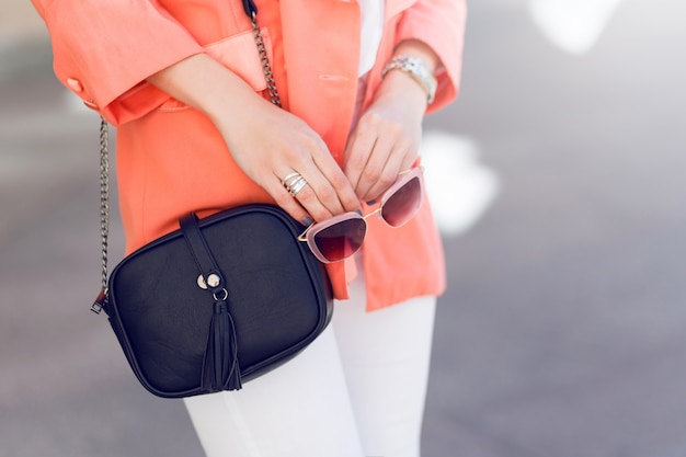 Mujer hermosa joven que camina en la ciudad vieja en la ropa de moda casual glamour, chaqueta rosa. Temporada de primavera u otoño, clima soleado. Detalles