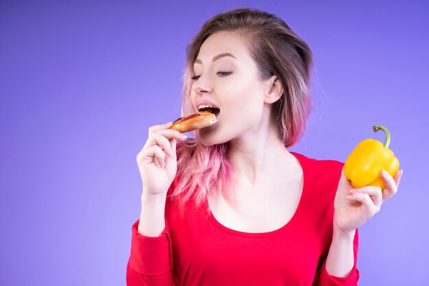 Mujer hermosa joven que come una rebanada de pizza y una pimienta