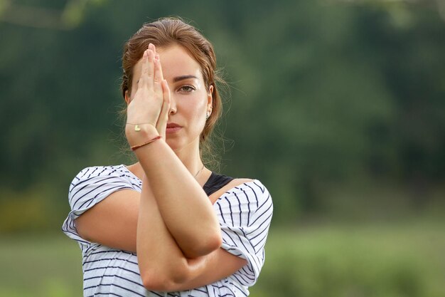 Mujer hermosa joven que hace ejercicio de yoga en el parque verde. Concepto de fitness y estilo de vida saludable.