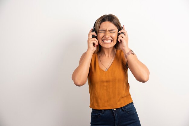 Mujer hermosa joven que lleva puestos los auriculares sobre el fondo blanco.