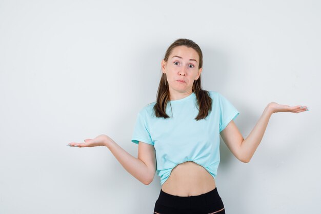 Mujer hermosa joven que muestra un gesto de impotencia en camiseta y que parece desconcertado. vista frontal.