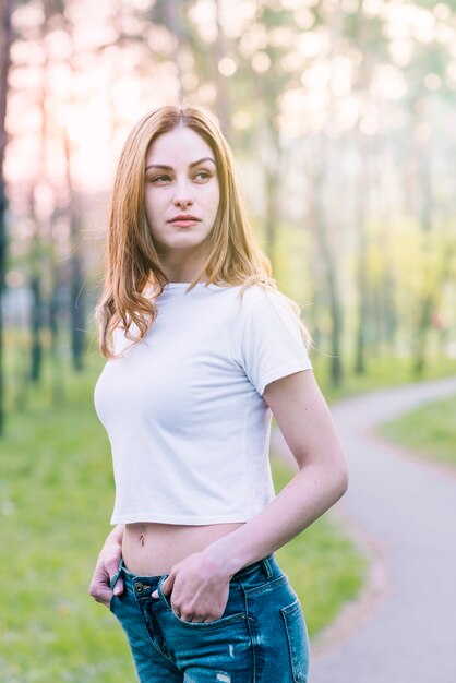 Mujer hermosa joven que presenta en parque verde