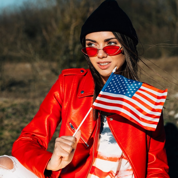 Foto gratuita mujer hermosa joven que sostiene la bandera americana