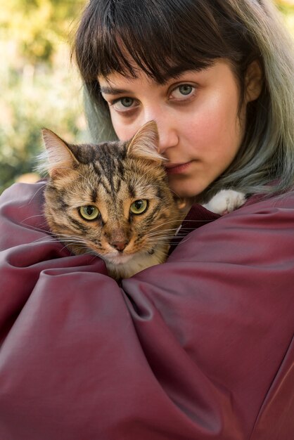 Mujer hermosa joven que sostiene el gato de gato atigrado