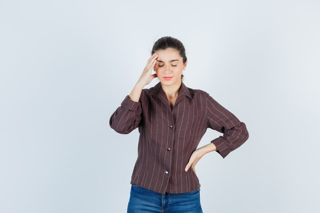 Mujer hermosa joven que sufre de dolor de cabeza en la chaqueta y parece doloroso. vista frontal.