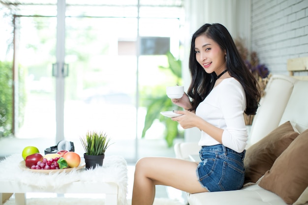 Mujer hermosa joven que usa un ordenador portátil en casa.