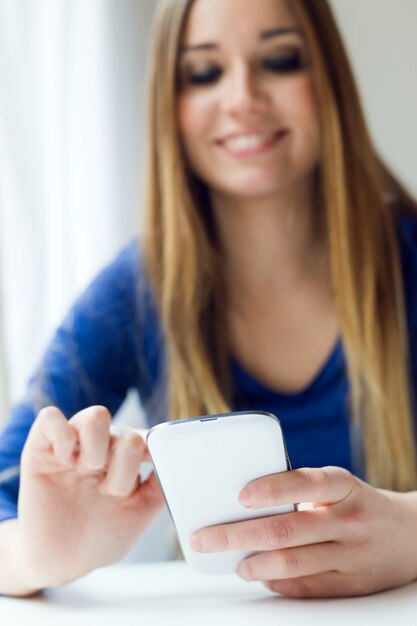 Mujer hermosa joven que usa su teléfono móvil en el país.