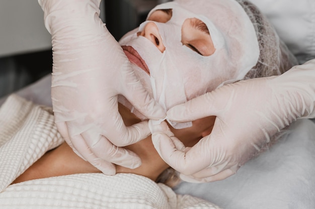 Foto gratuita mujer hermosa joven recibiendo un tratamiento de mascarilla para la piel en el spa