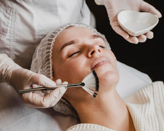 Mujer hermosa joven recibiendo un tratamiento para la piel de la cara en el spa