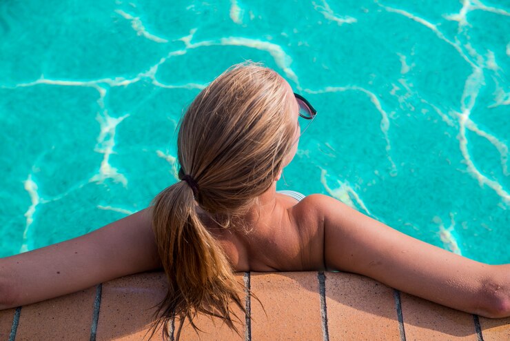 Una mujer hermosa joven relaja en la piscina. Concepto de bienestar. Spa y relajarse, la felicidad de la mujer.