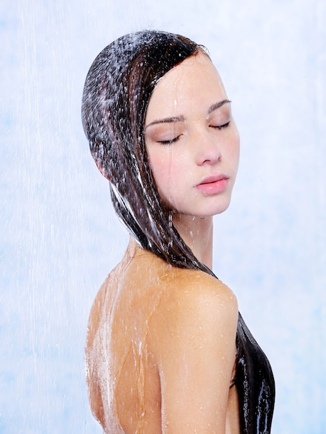 Mujer hermosa joven relajante tomando una ducha