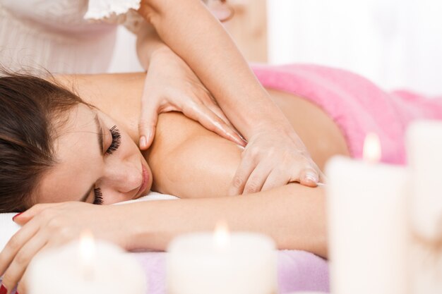 Mujer hermosa joven en el salón de spa con masaje relajante corporal