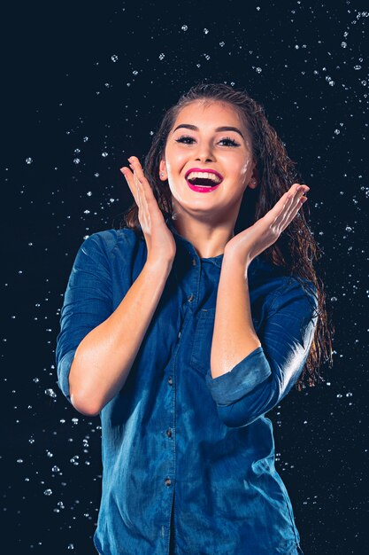 Mujer hermosa joven bajo salpicadura de lluvia