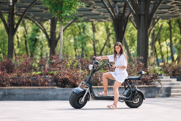 Mujer hermosa joven y un scooter eléctrico, chica moderna, nueva generación, transporte eléctrico, transporte ecológico