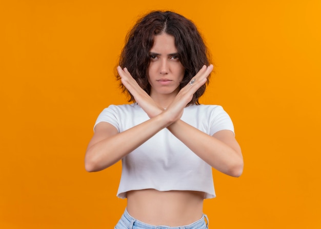 Mujer hermosa joven seriamente mirando parada gesticulando en pared naranja aislada con espacio de copia