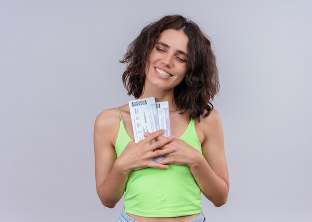 Foto gratuita mujer hermosa joven sonriente que sostiene los billetes de avión en la pared blanca aislada