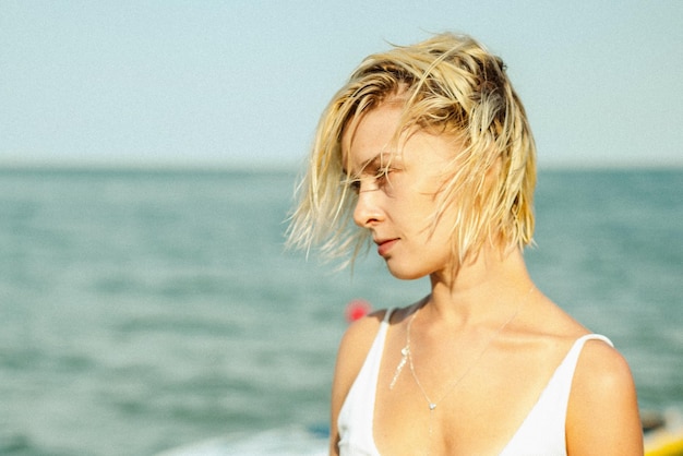 mujer hermosa joven en un traje de baño blanco en la playa.