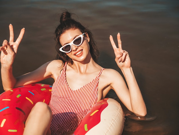 Foto gratuita mujer hermosa joven en traje de baño y gafas de sol flotando en el mar