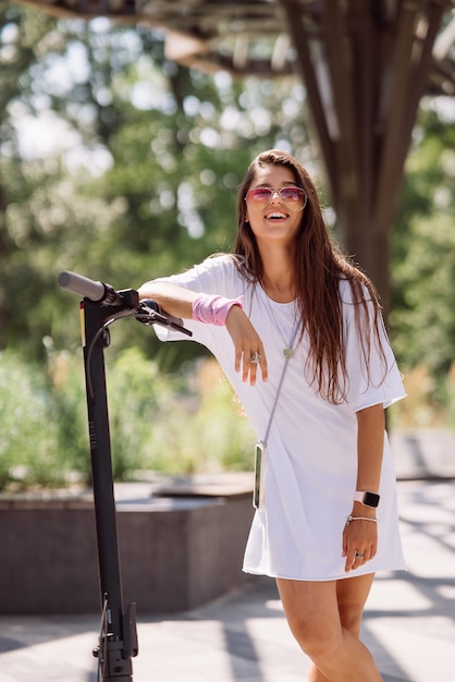 Mujer hermosa joven y un transporte ecológico scooter eléctrico