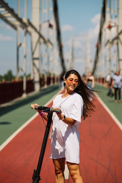 Mujer hermosa joven y un transporte ecológico scooter eléctrico