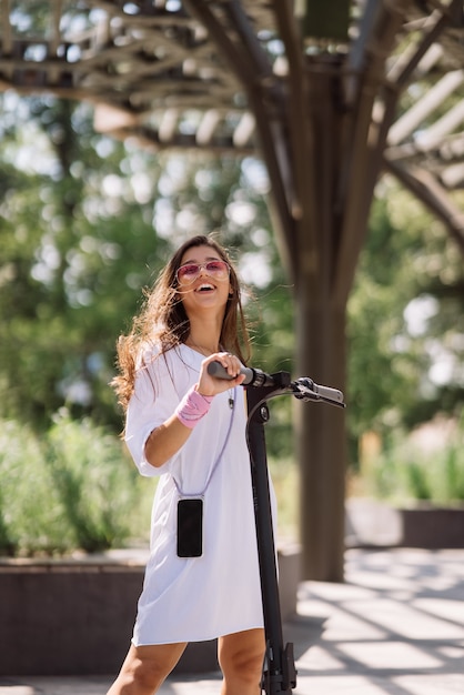 Mujer hermosa joven y un transporte ecológico scooter eléctrico